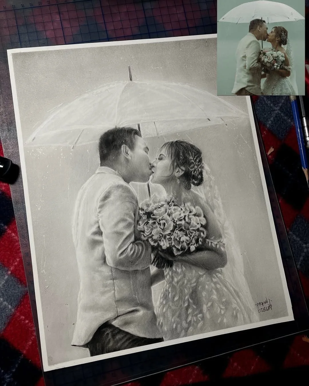 A black and white wedding portrait of a couple sharing a kiss under an umbrella, with the bride holding a bouquet of flowers.