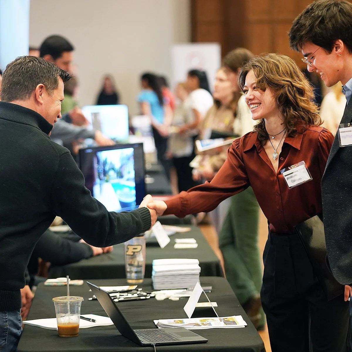 A smiling student shaking hands with a prospective design firm project manager