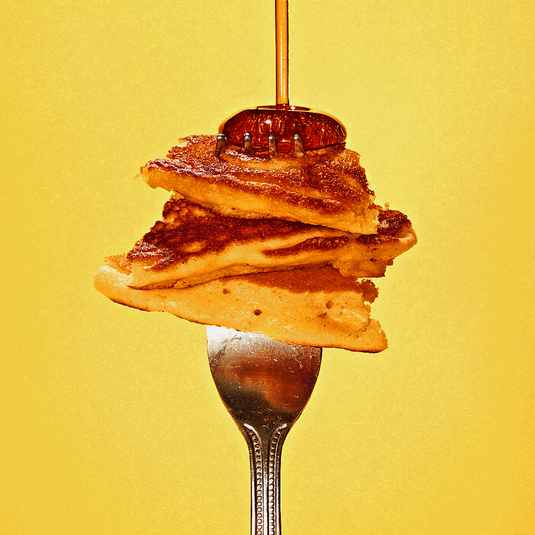 A fork with three slices of cooked apple pie stacked in a cone shape, topped with a syrup or caramel drizzle against a yellow background.