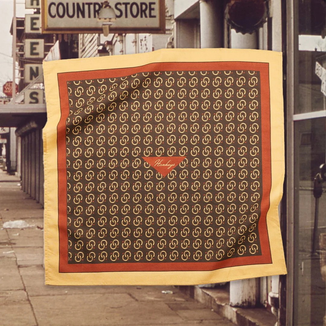 A yellow and red patterned scarf hanging outside a store with a sign that says 'Country Store' in the background.