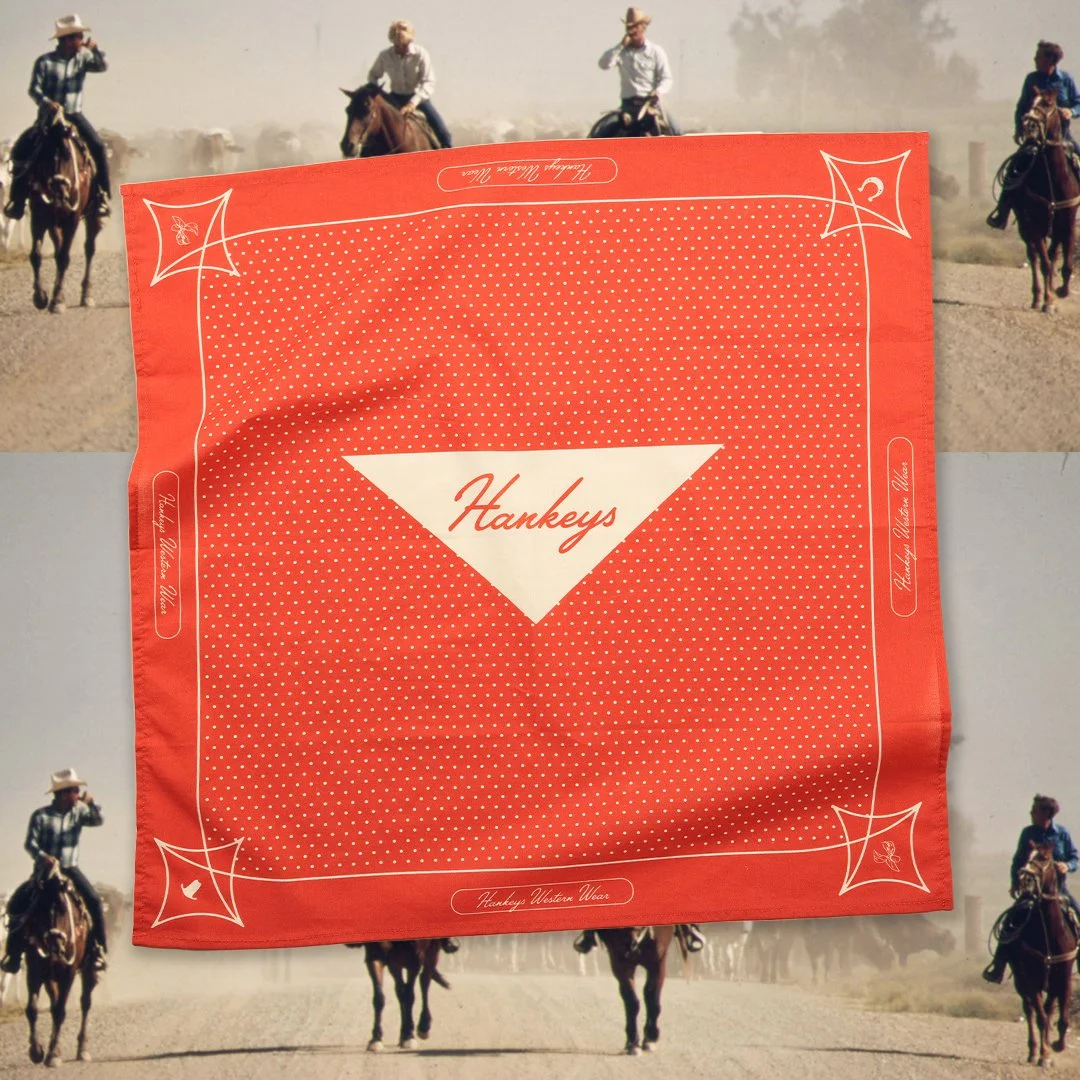 A red bandana with the word "Hankeys" written in white in the center. The bandana has a diamond pattern and decorative white corner designs. The background features four cowboys riding horses on a dusty plain.