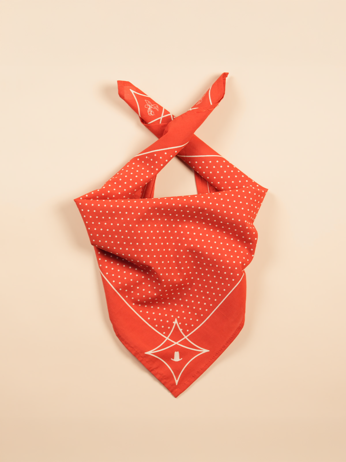 Red bandana with white polka dots folded to resemble a face mask.
