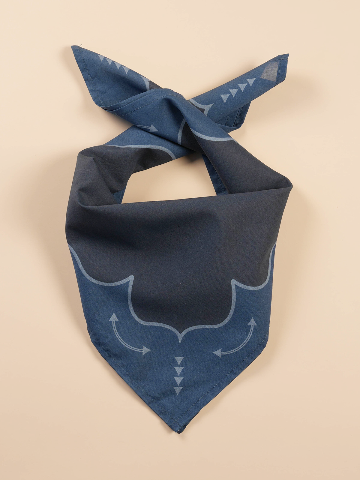 Blue bandana with white geometric patterns, folded with knots at the top, against a plain beige background.