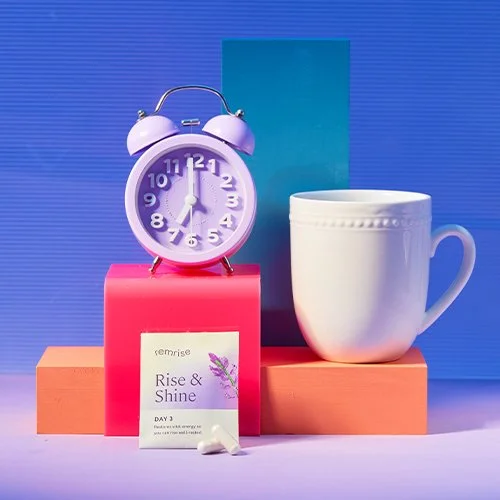 A pink alarm clock showing 9:00, a white mug, a lavender scent sachet labeled "Rise & Shine" on a pink box, all set against a blue background with colorful blocks.