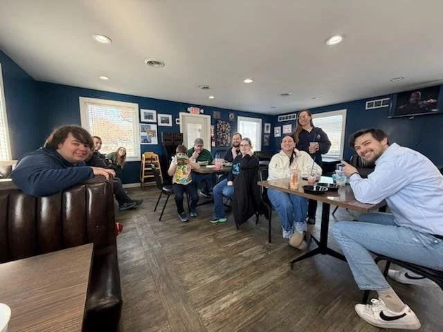 Members of Chuck & Bev's family sitting around inside Trekker's restaurant, smiling for the camera and sharing some dirty sodas.