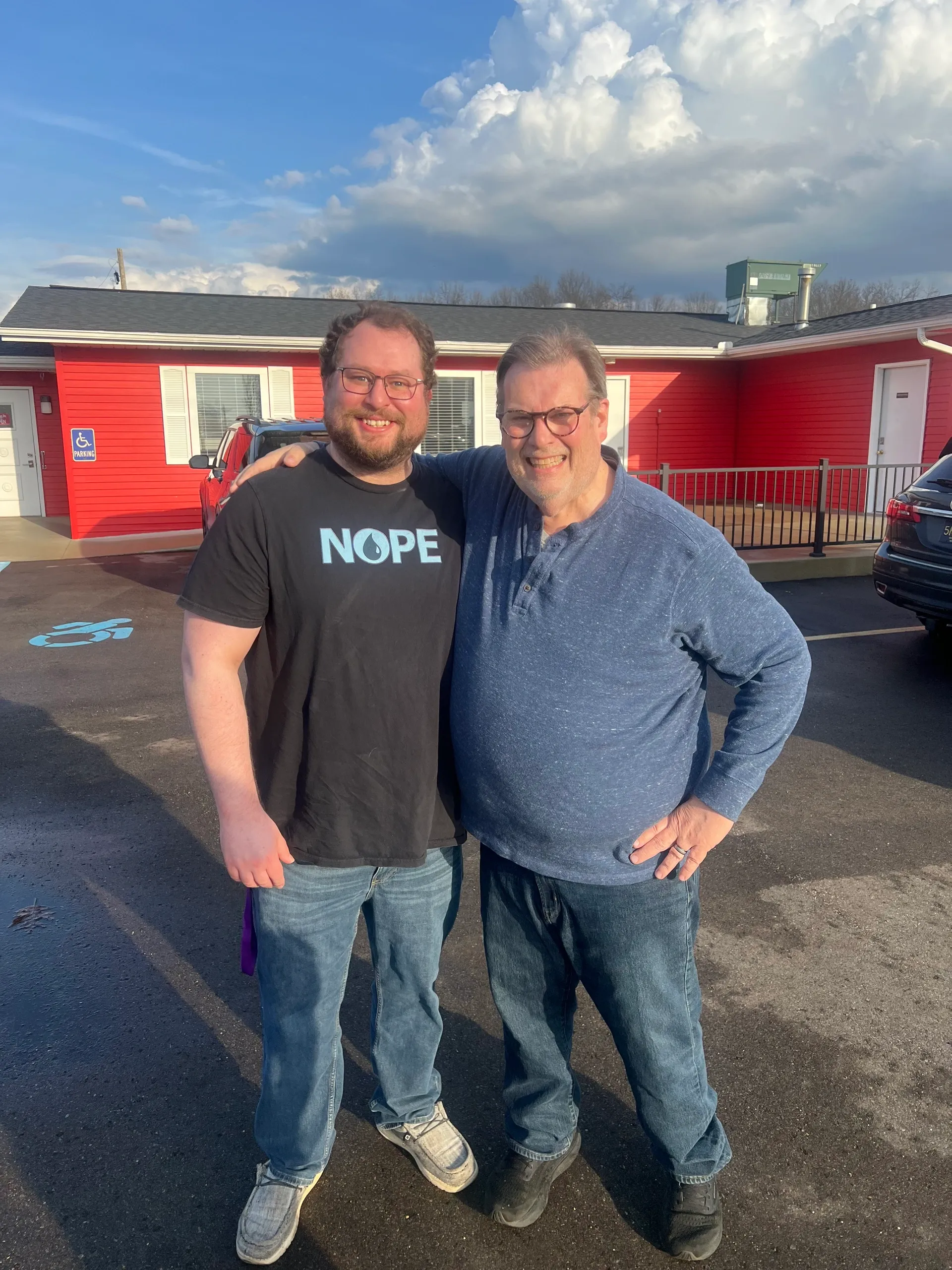 2 men standing outside of Trekkers in a friendly embrace