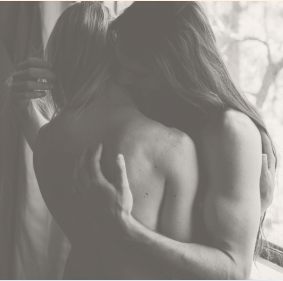 Two individuals sharing an intimate embrace, with one kissing the other's shoulder.