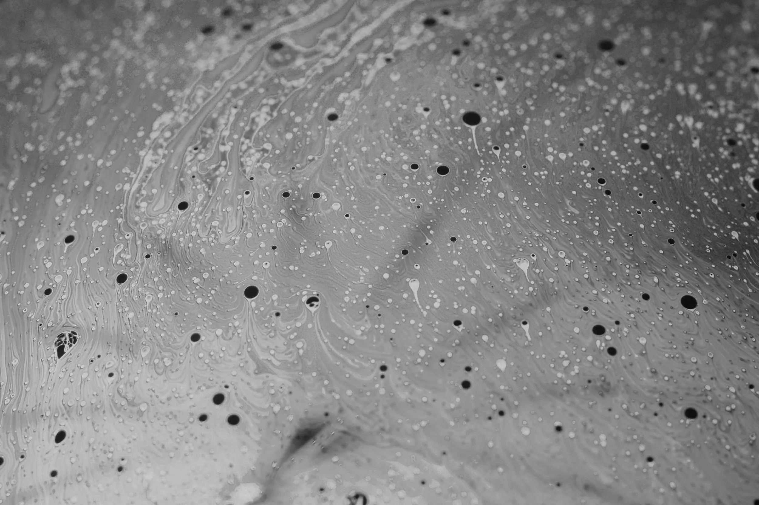 Black and white abstract image with swirling patterns and circular spots of various sizes.