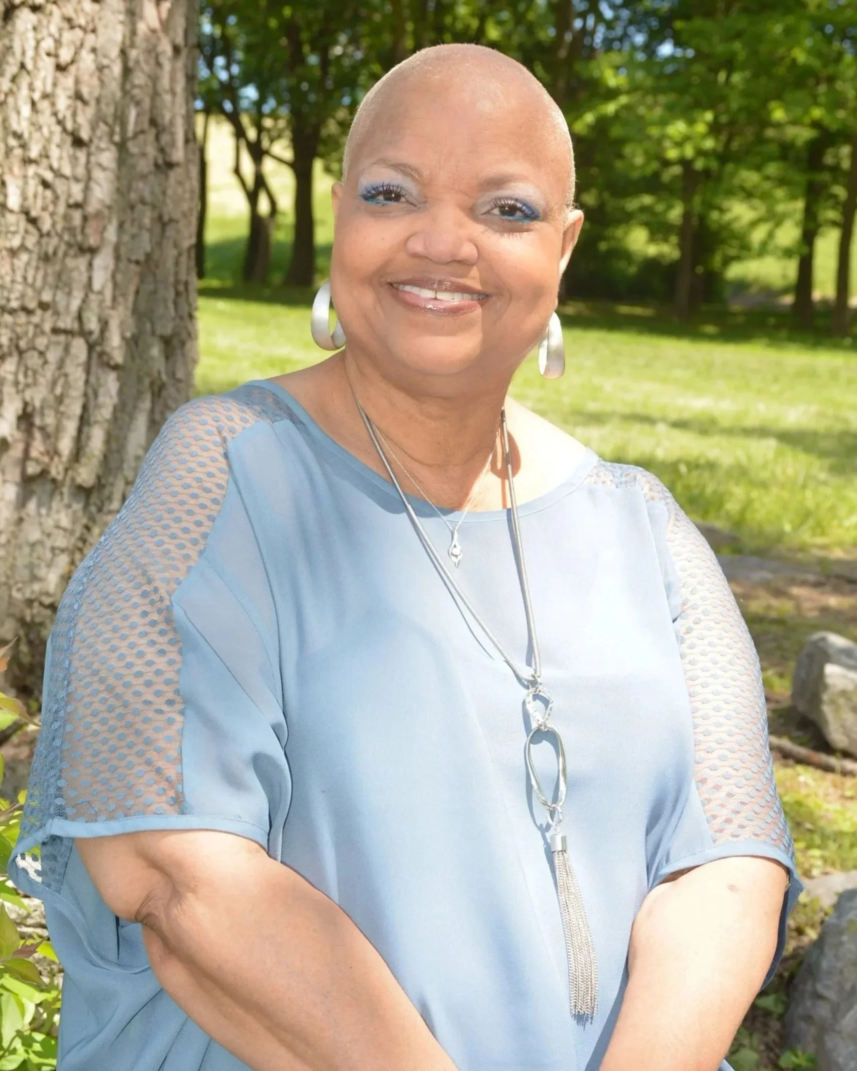 Cynthia Elaine Davenport, the woman honored by Cynthy's Kids, Inc., smiling warmly outdoors in a blue top, embodying the faith, grace, and resilience that inspired this organization.
