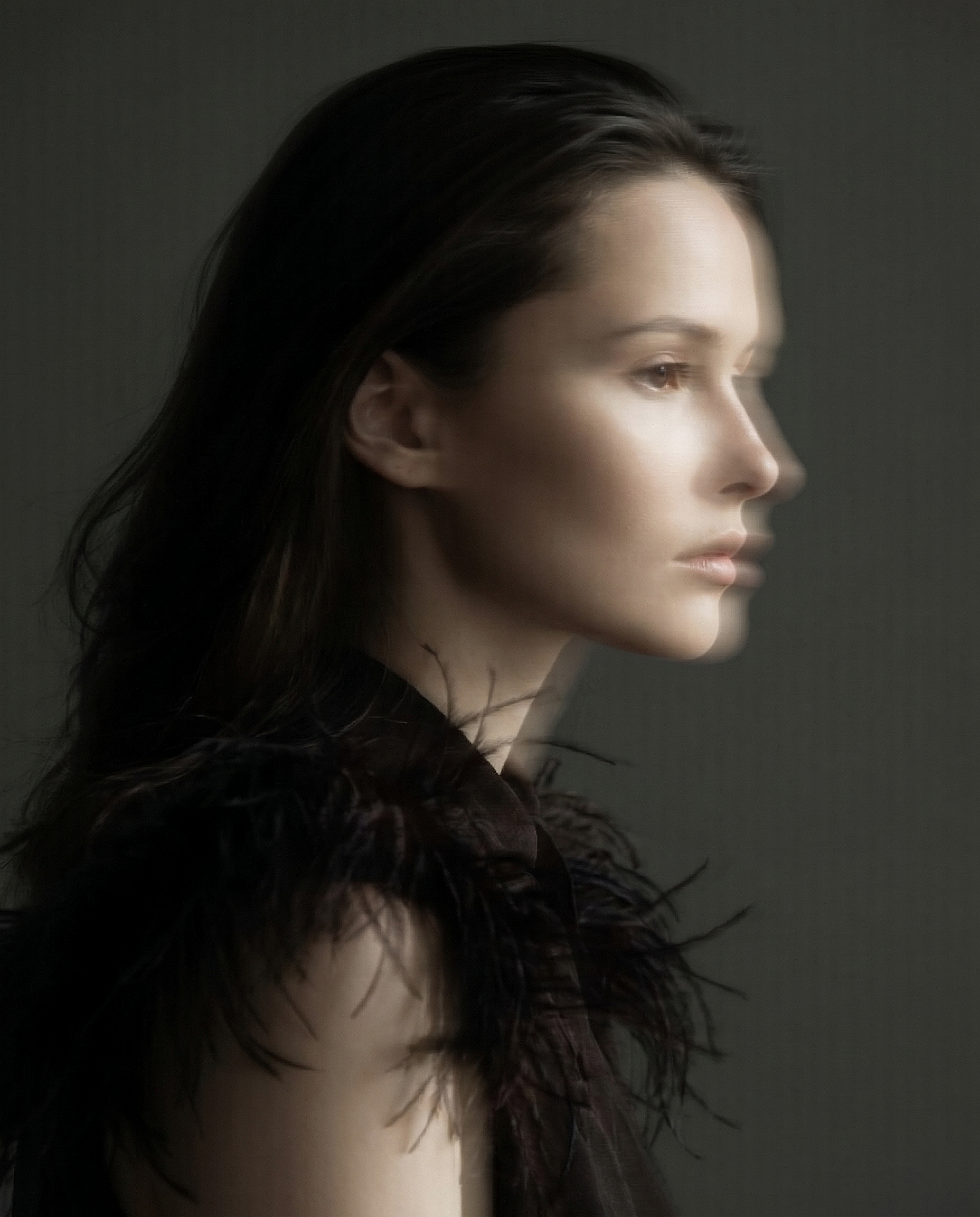 Side profile of a woman with dark hair against a dark background.