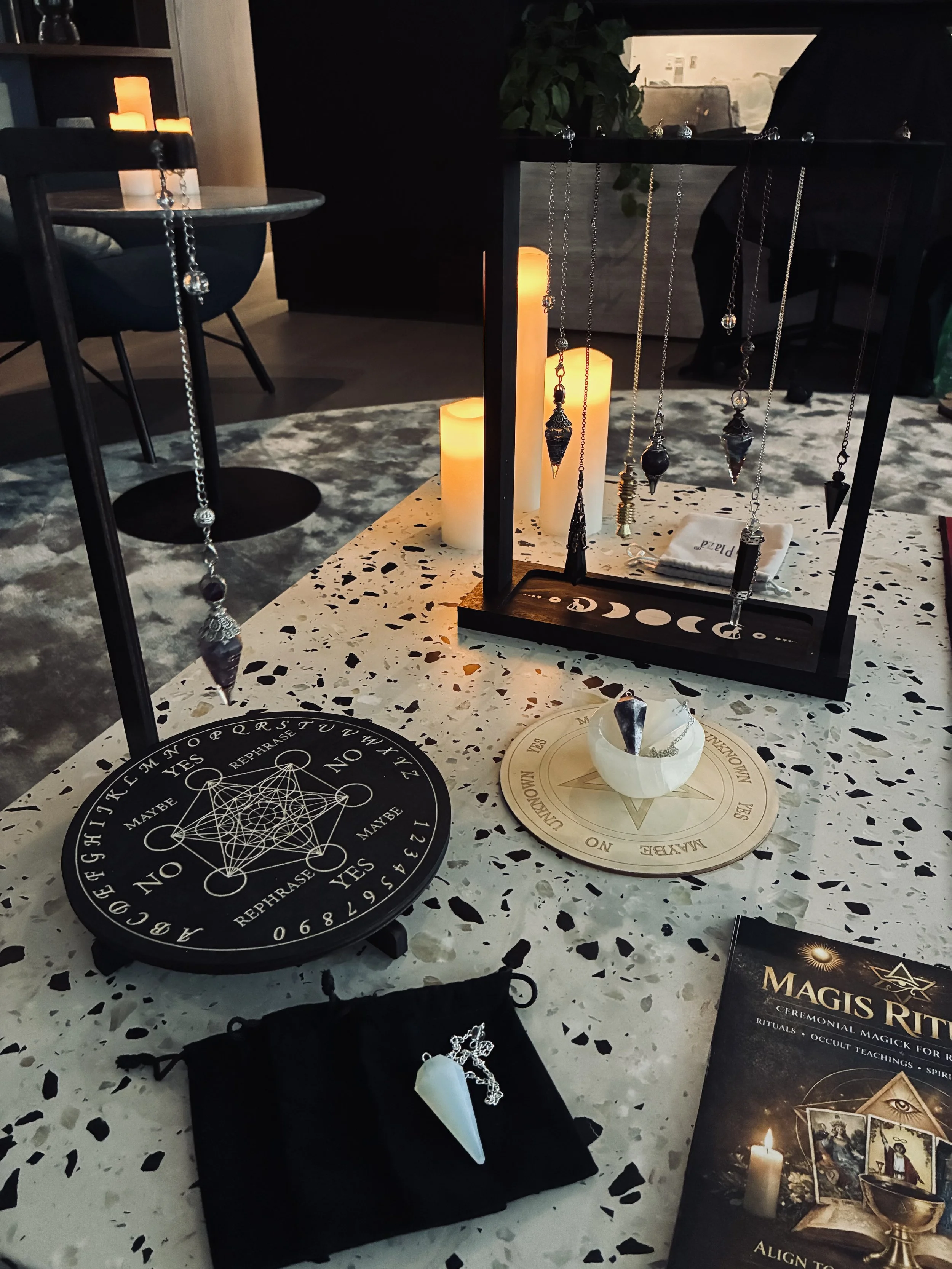 Various occult and magic items displayed on a table, including charms, symbols, candles and a 'Magis Ritualis' marketing handout.
