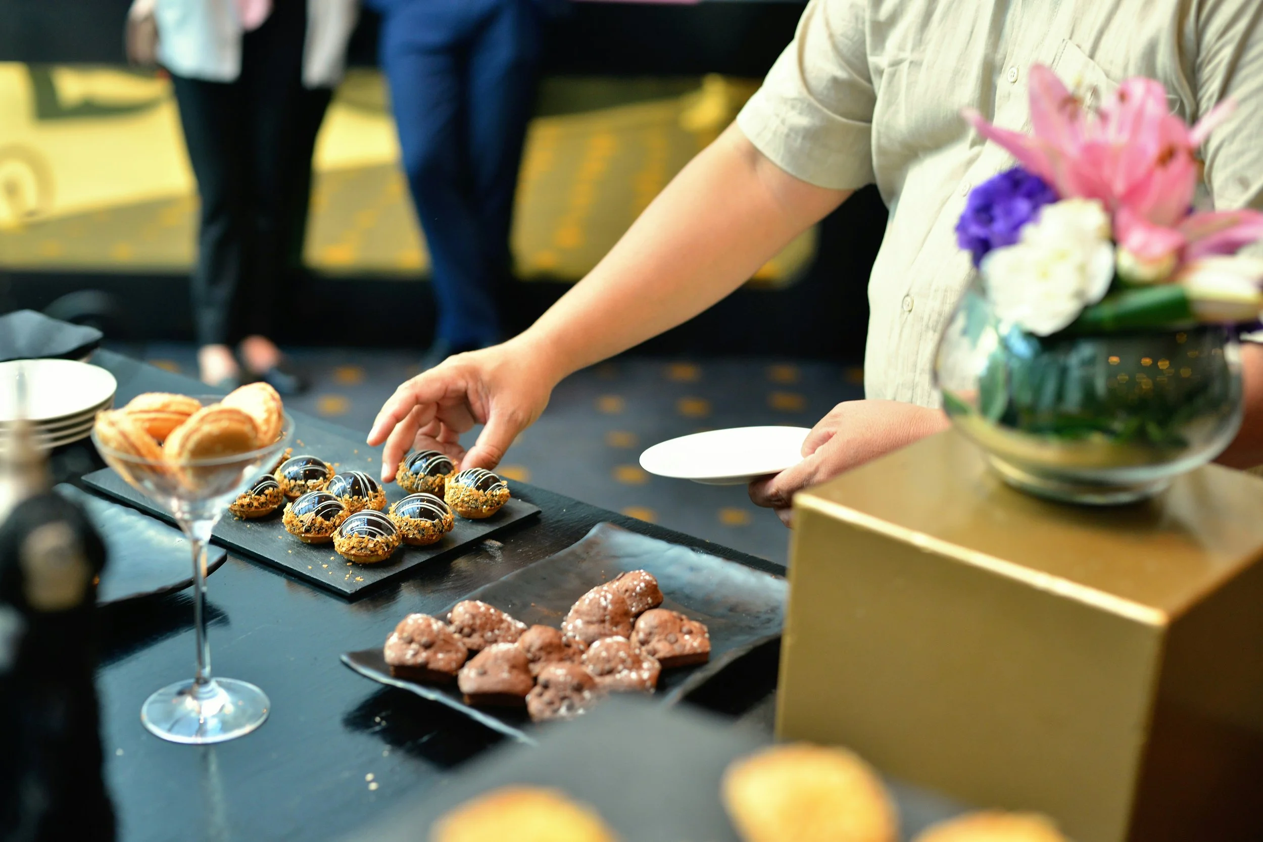 Guest selecting bite-sized desserts from a catered pastry display.