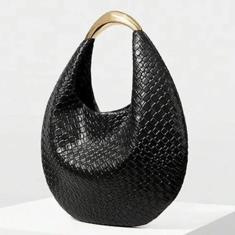 Sculpted, polished, and quietly dramatic, this crescent evening bag brings a touch of retro refinement to modern dressing. The woven PU leather adds subtle texture, while the metal top handle introduces a cool, architectural contrast. 
A small piece 