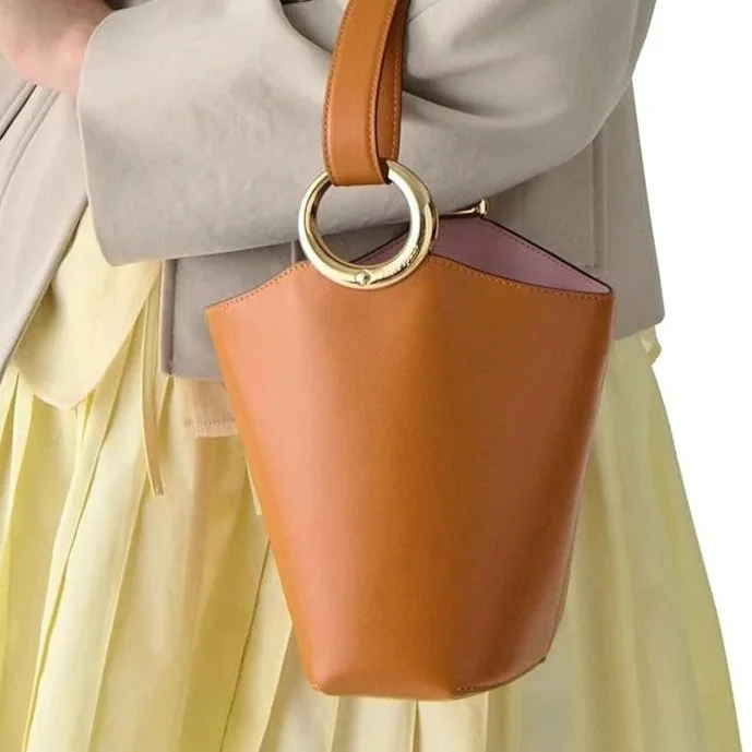 The Halo mini Bucket feels like something you’d notice first in motion rather than in passing. 
Crafted in fine grain leather, it carries that polished ease often associated with European city dressing. The mini scale keeps it light and modern, while