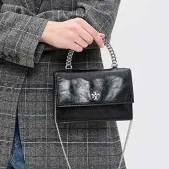The Tory Burch Kira distills evening elegance into its most essential form. Softly structured with a relaxed, deconstructed feel. The signature chain strap brings a subtle gleam, while the top handle offers a more intimate, hand-held option, like som