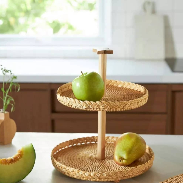 Jules 2-tier Rattan and Wood Fruit Stand.
Timeless in design, this serving tray will be treasured for years to come. This fruit stand is hand-woven and features a lovely grain pattern from the natural wood used for the center and the rattan used for 