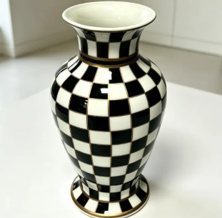 A bold black and white checkerboard ceramic vase, finished with bronze detailing for an unexpected bit of shine. Graphic and a little maximalist, it holds its own as a centerpiece or blends into a room full of collected pieces.