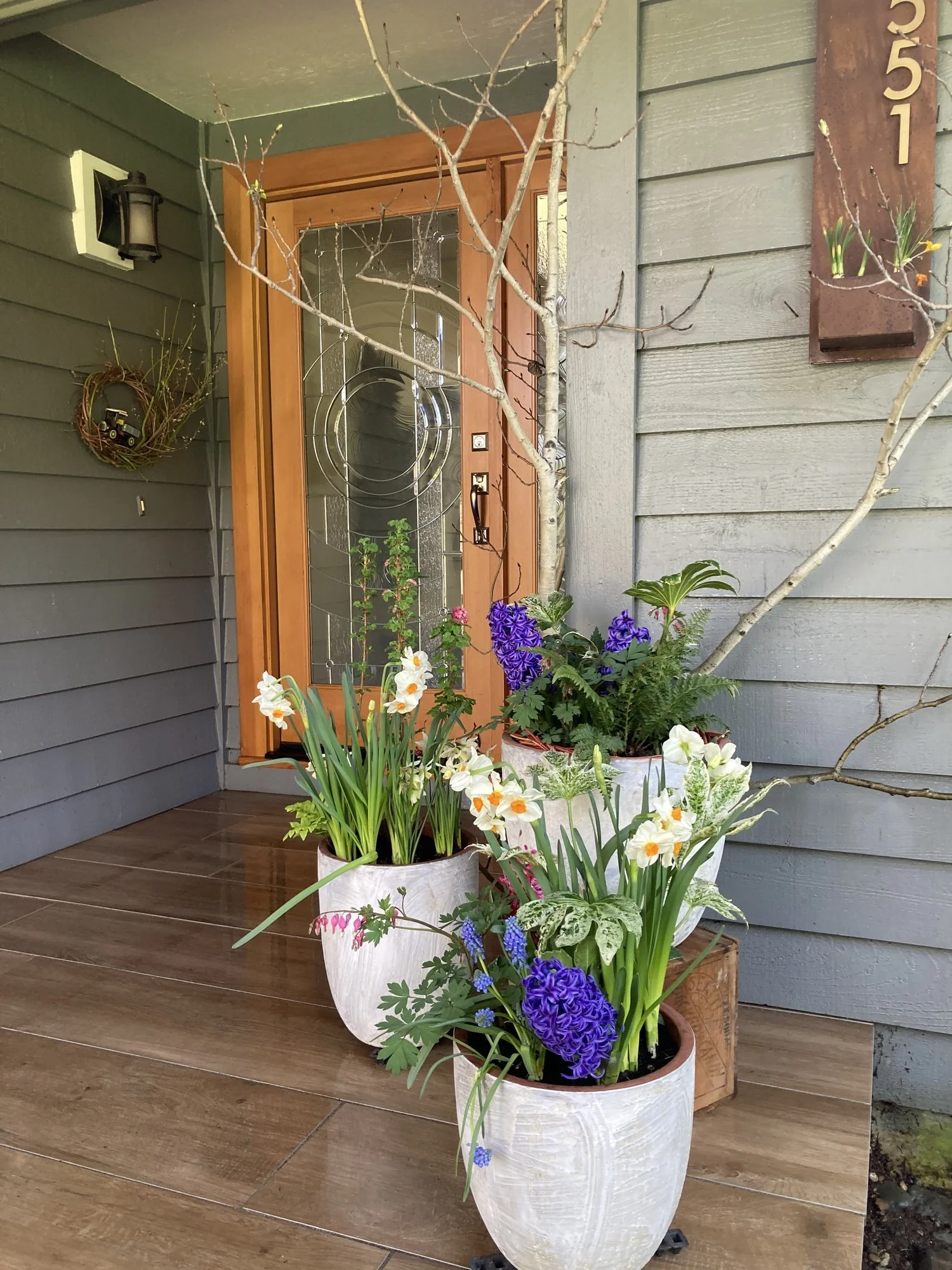 Front porch styled with custom seasonal planters in full bloom