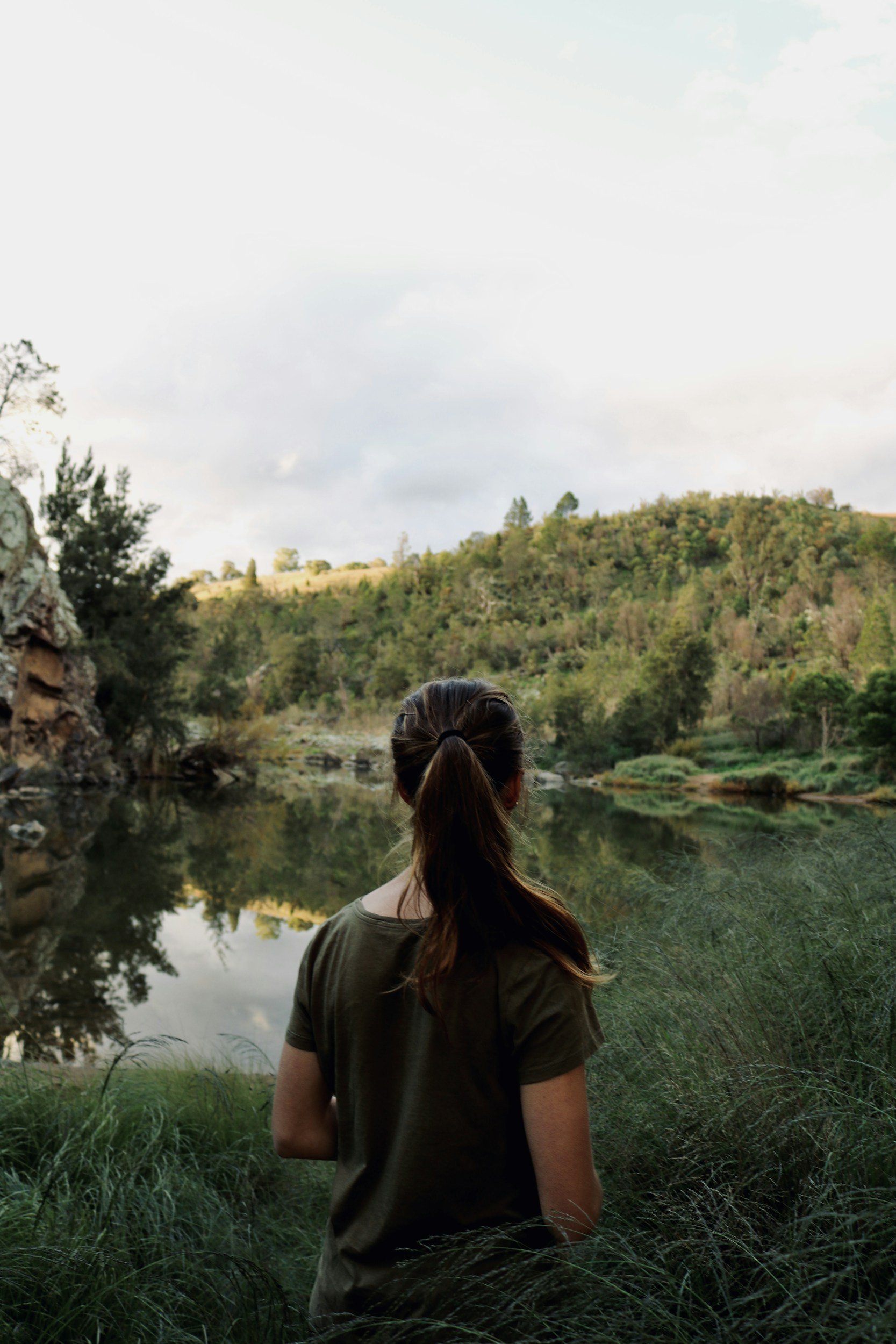 Woman looking at a pond, standing in the woods