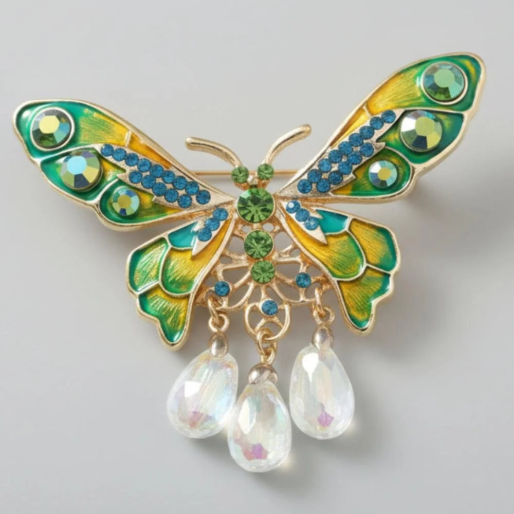 Colorful enamel and gemstone butterfly brooch with clear dangly beads on a gray background