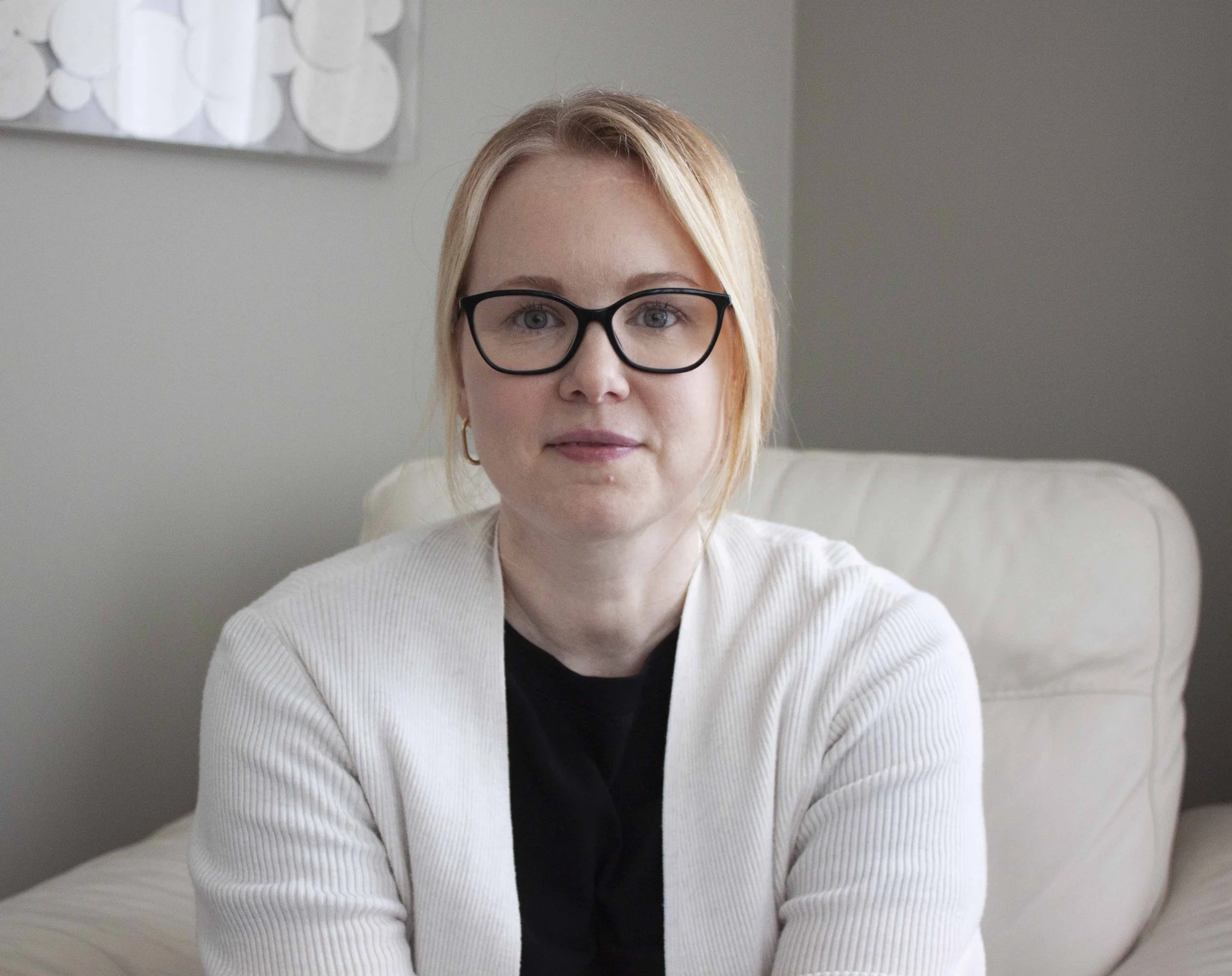 Therapist and Supervisor, Julie Thomason seated in a cream coloured chair, looking directly at the camera with a warm smile on her face.