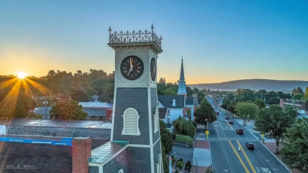 Sunset over a small town with a clock tower and church steeple.