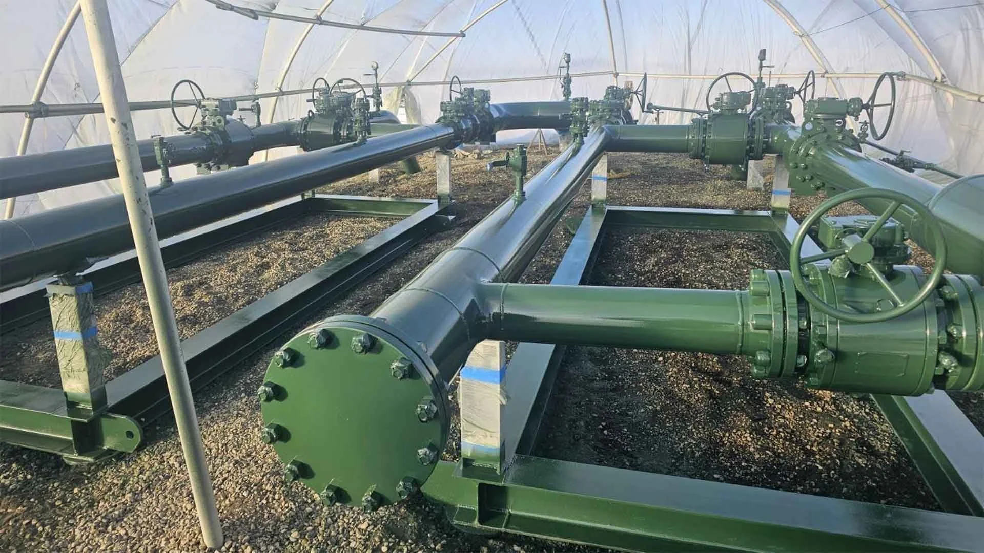 Green industrial pipes and valves inside a greenhouse
