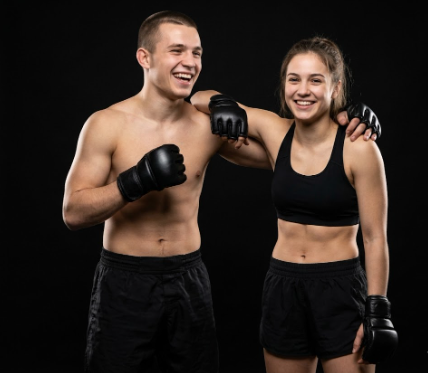 Un hombre y una mujer con guantes de boxeo, sonriendo y posando en un fondo negro.