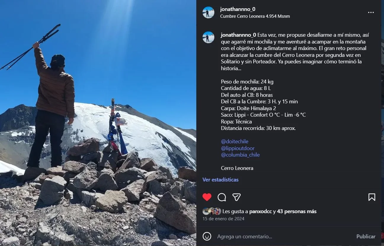 Persona de espaldas en la cima de una montaña, sosteniendo unos bastones de senderismo en el aire, con un fondo de cumbre nevada y cielo despejado.