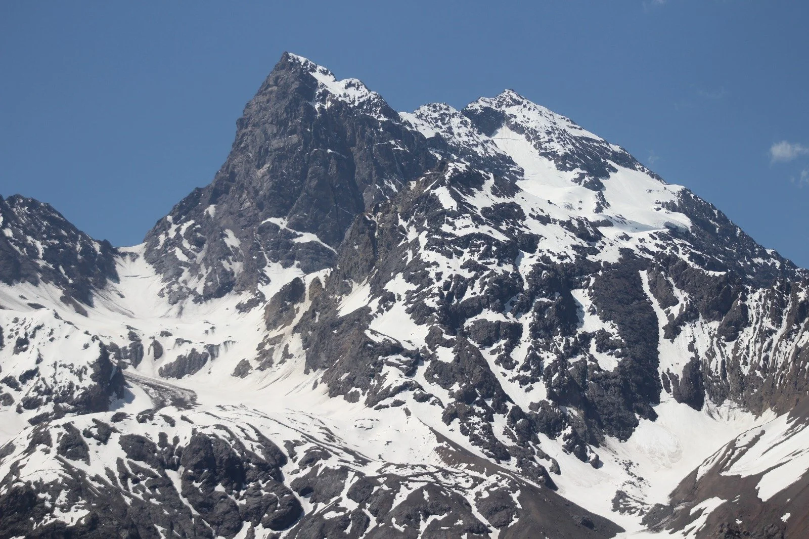 Montaña nevada y rocosa con picos escarpados y nieve en las cumbres, bajo cielo azul