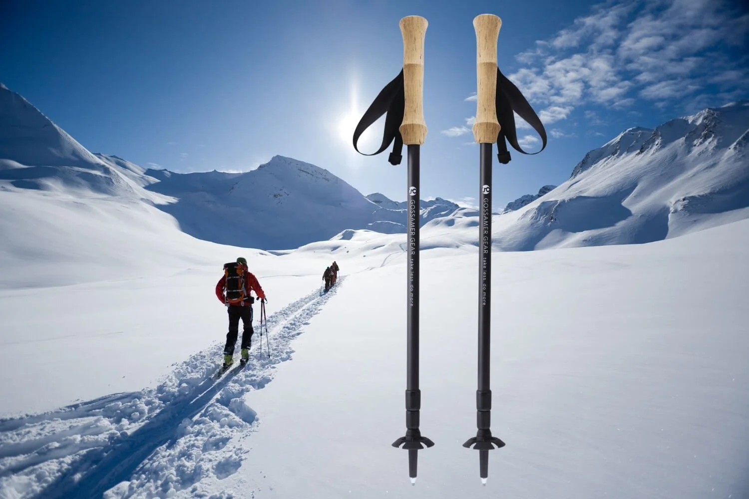 Dos bastones de senderismo con empuñaduras de madera y correas negras, colocados en la nieve en un paisaje de montañas nevadas con excursionistas al fondo