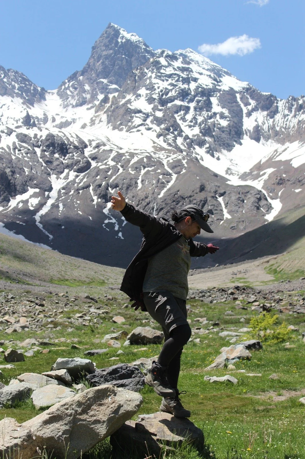 Persona caminando en un paisaje montañoso con picos nevados en el fondo.