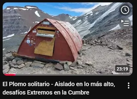 Tienda de campaña roja en una montaña con nieve y rocas, en un entorno de alta altitud.