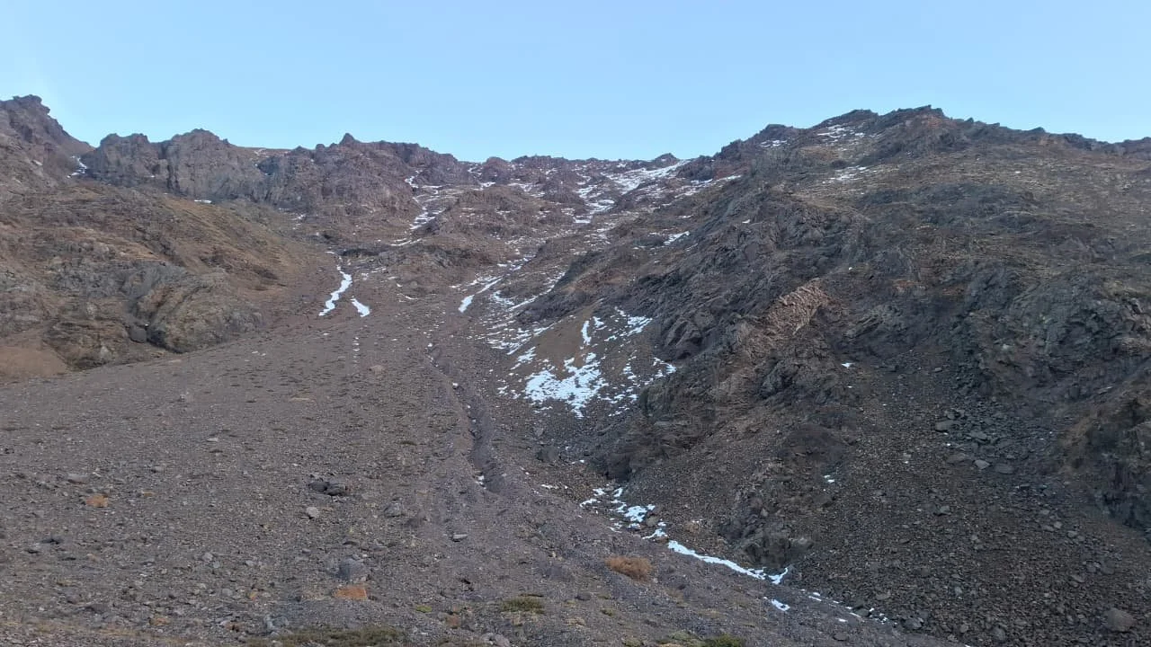 Montaña rocosa con algunos restos de nieve y un cielo despejado.