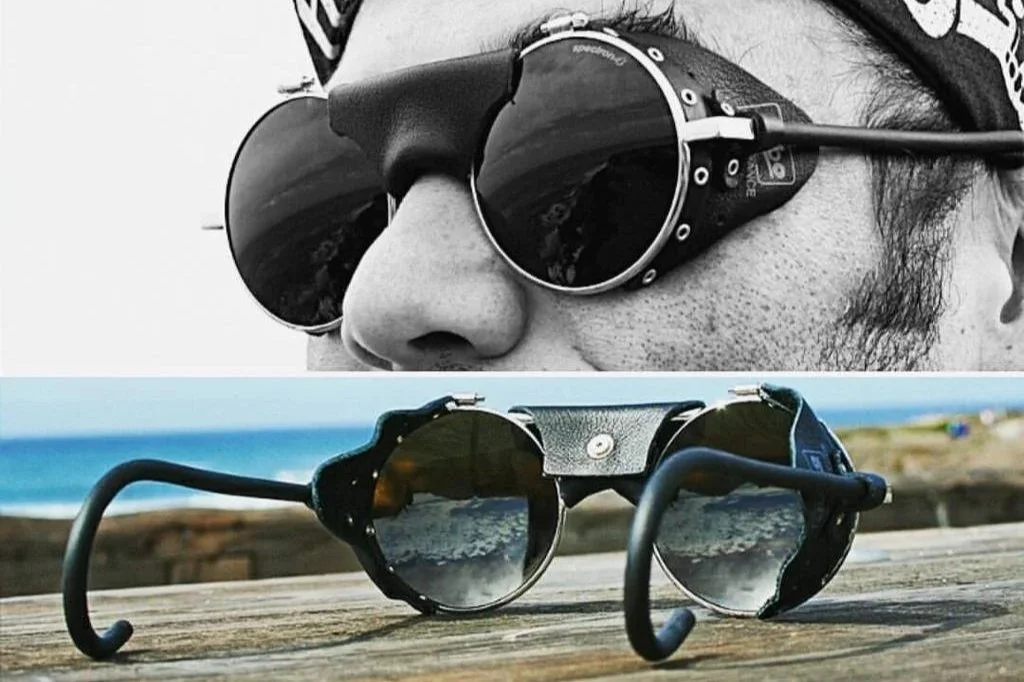 Gafas de sol: en la parte superior, una persona lleva gafas grandes, de cristal oscuro, en un primer plano en blanco y negro. En la parte inferior, unas gafas similares están colocadas sobre una mesa de madera en un entorno junto a la playa, con fondo del mar y cielo.