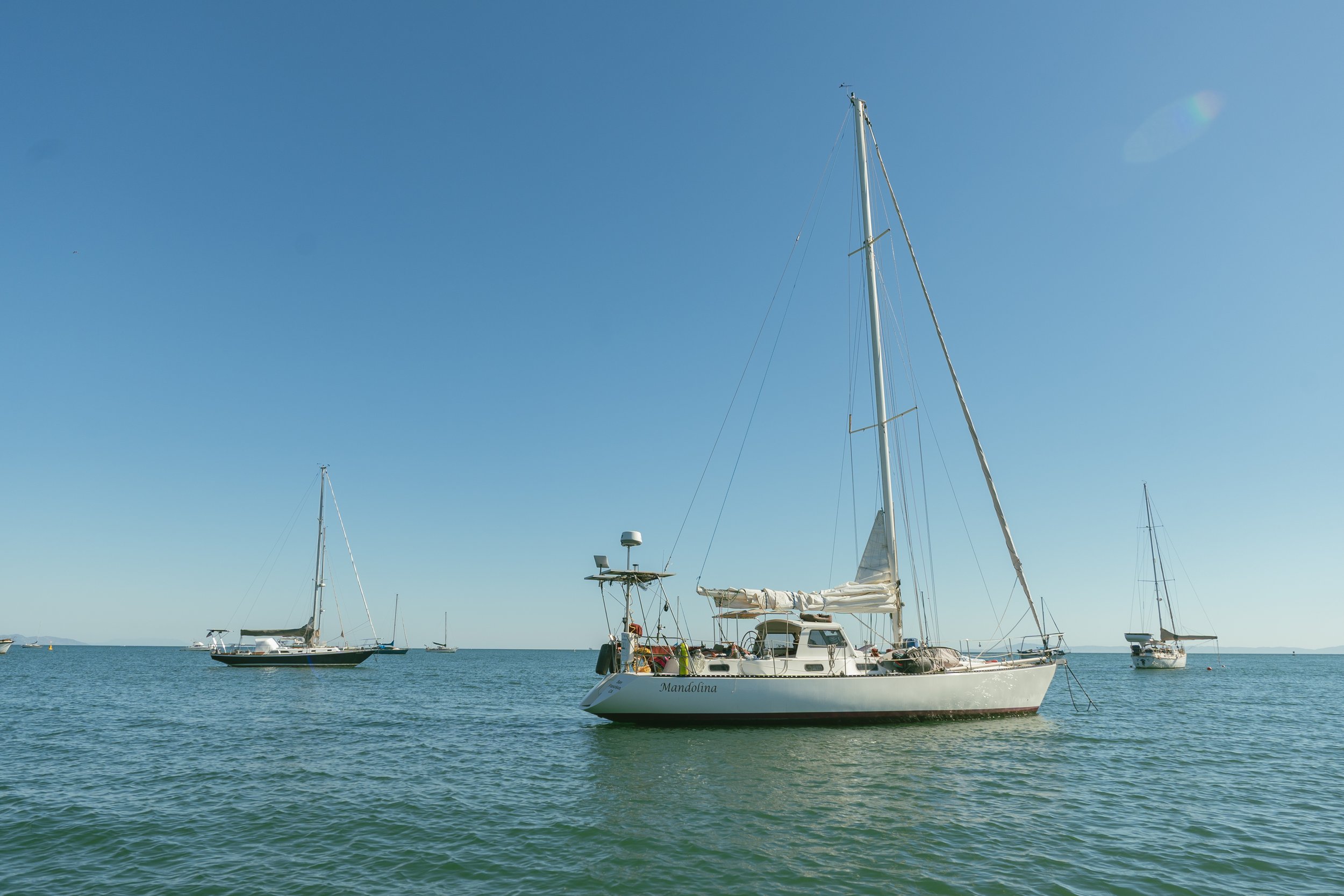 Sailboats anchored in a calm sea under clear blue sky