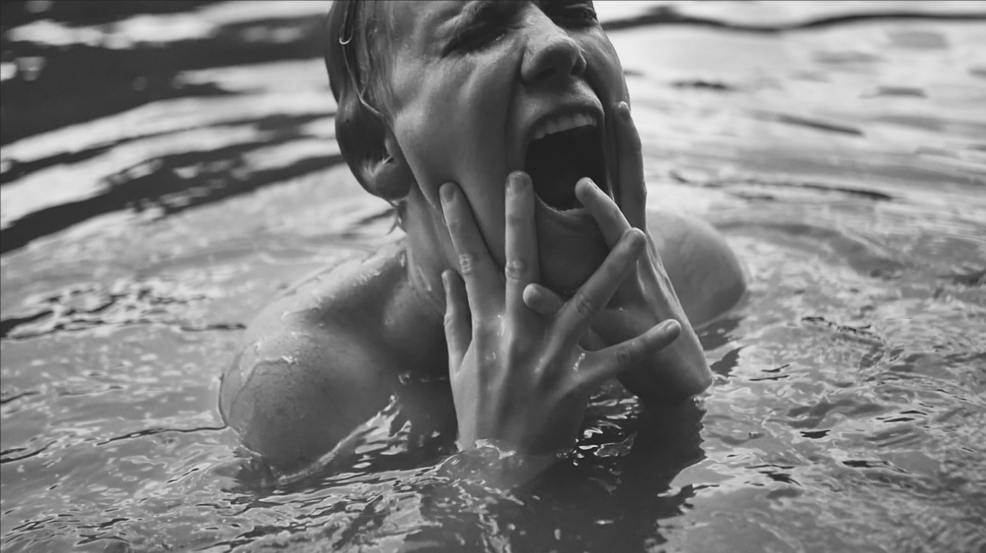 Film still of a person emerging from the water, screaming
