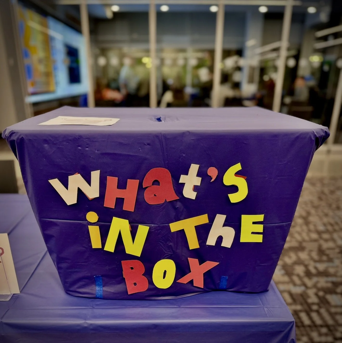 A hand-made box is decorated with letters that spell out What's In the Box?