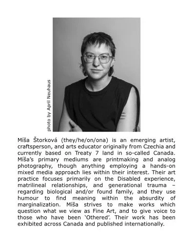 A photo of Míša Štorková (they/he/on/ona)  in black and white depicts them wearing glasses and a dark-coloured tank and a slight smile.
