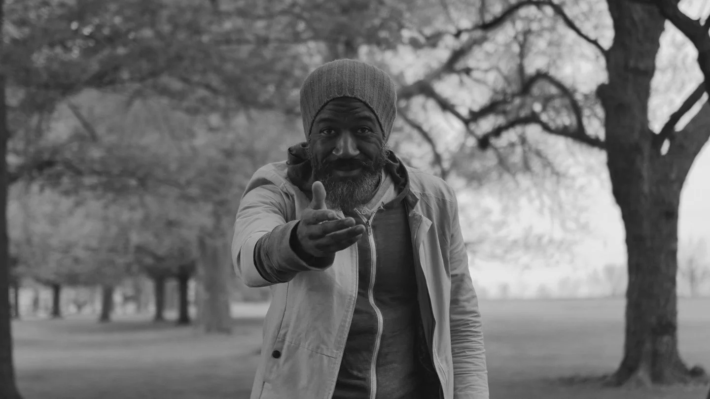 Film still of a man signing in ASL in a park