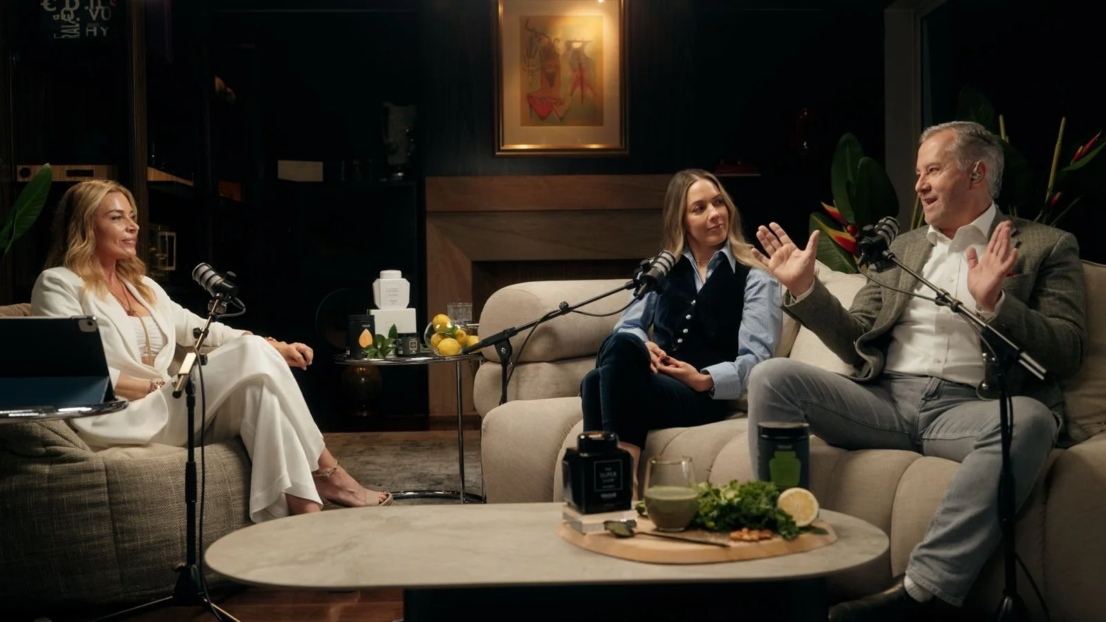 Cuatro personas participando en una entrevista o conversación en un estudio, con micrófonos y equipo de grabación, en un ambiente confortable y elegante.