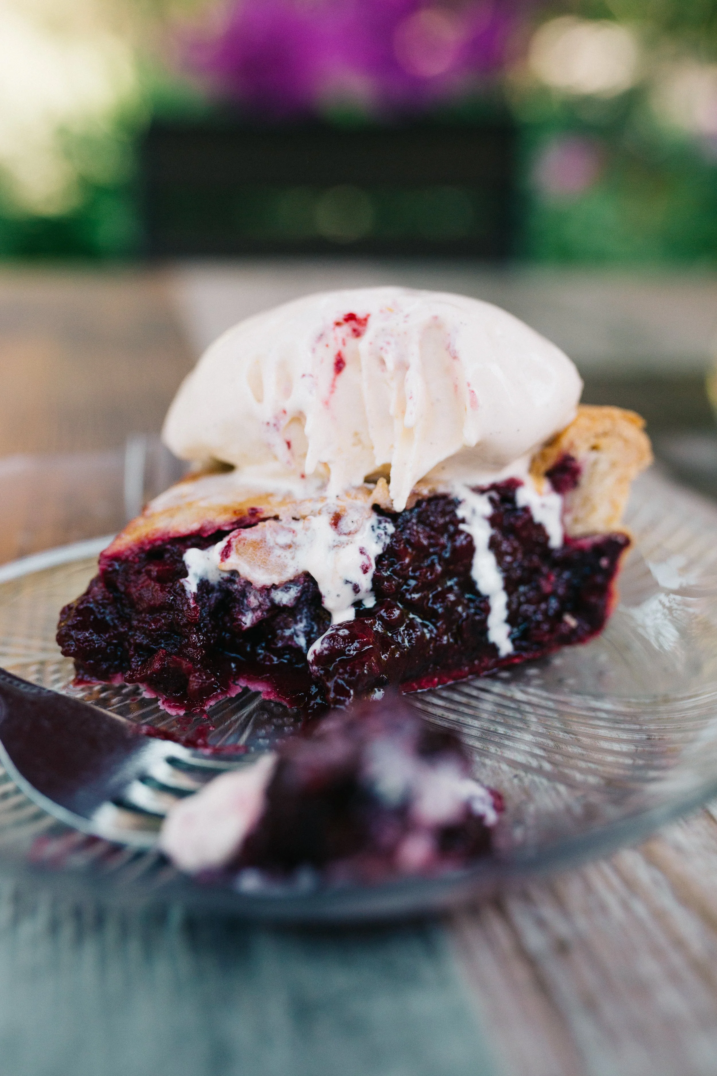 Slice of berry pie with whipped cream on top served on a glass plate