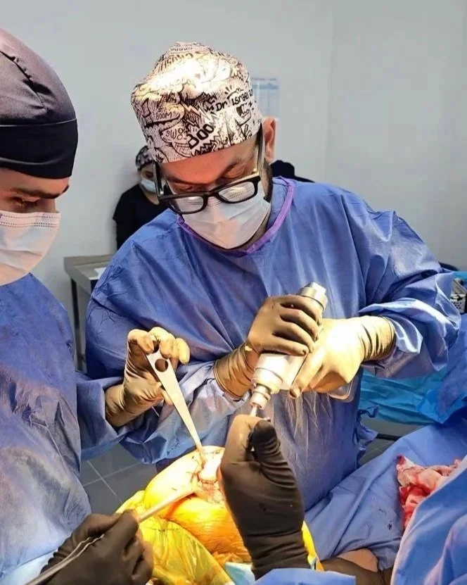 Equipo de cirujanos en un quirófano realizando una cirugía con instrumentos médicos y vestimenta quirúrgica.