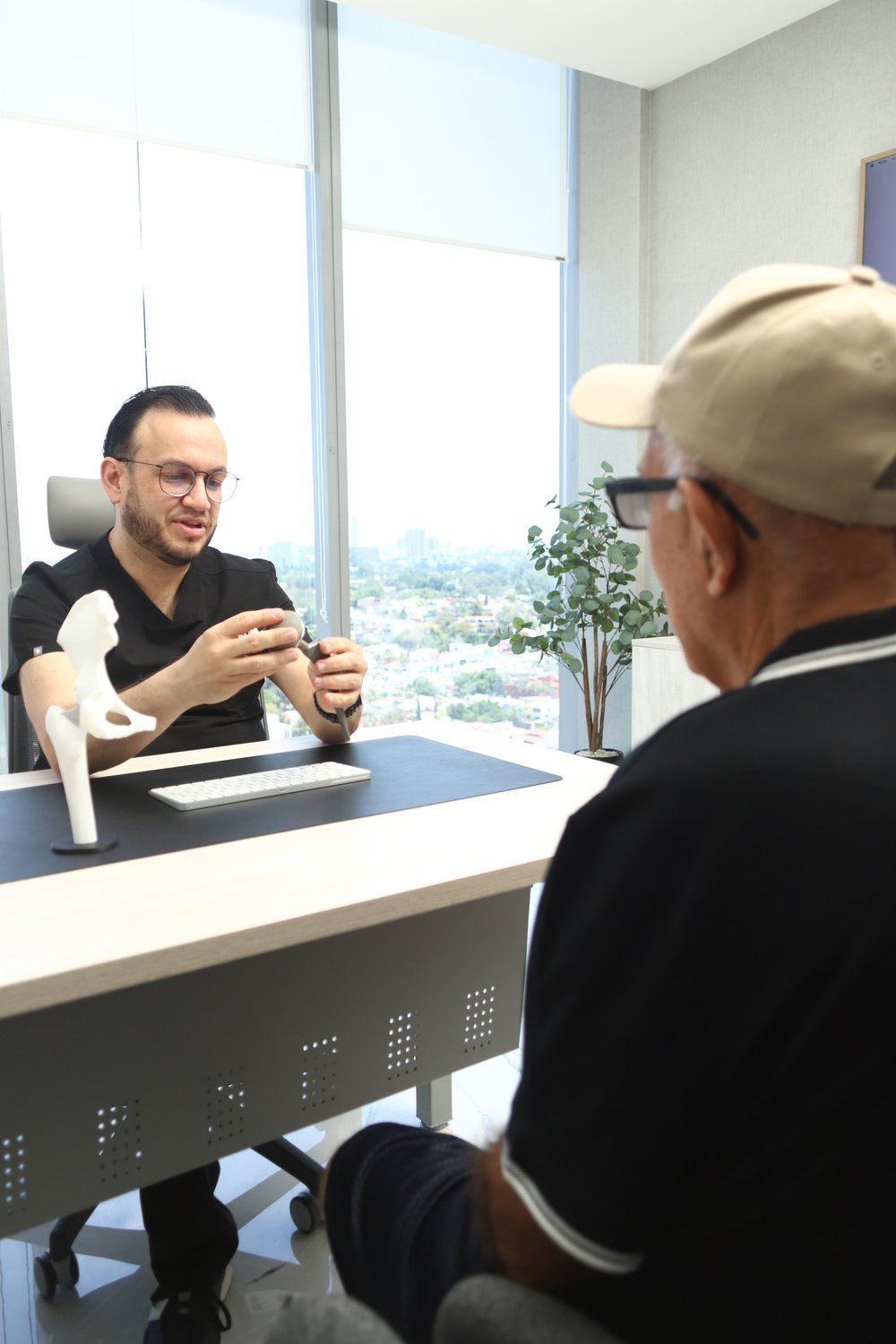 El Dr. Israel Romo, cirujano articular, explica una prótesis de cadera con un modelo en su consultorio en Guadalajara