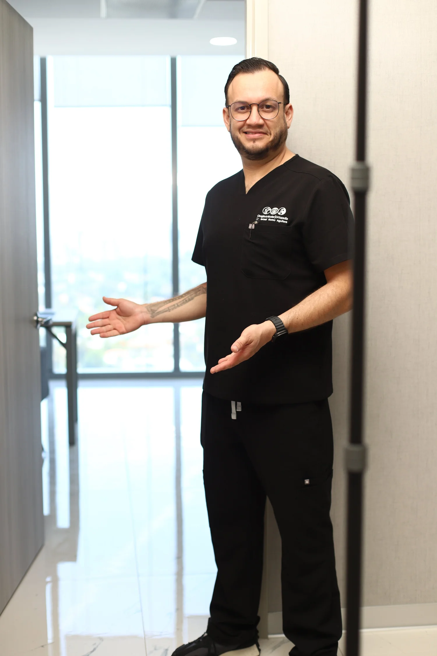Dr. Israel Romo, ortopedista en Guadalajara y Zapopan, recibe a sus pacientes en la puerta de su consultorio