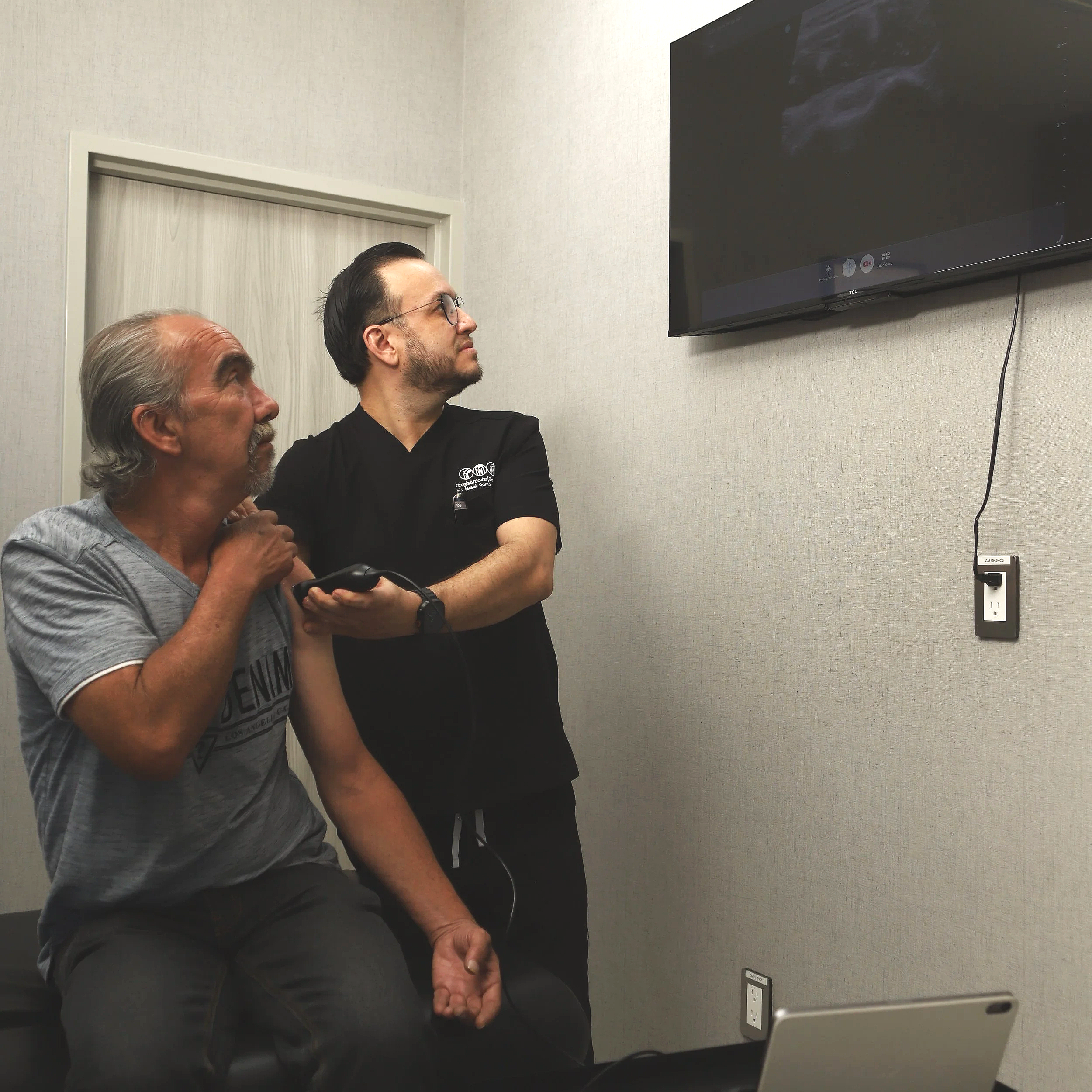 Dos hombres observando una pantalla de televisor en una sala de reuniones.