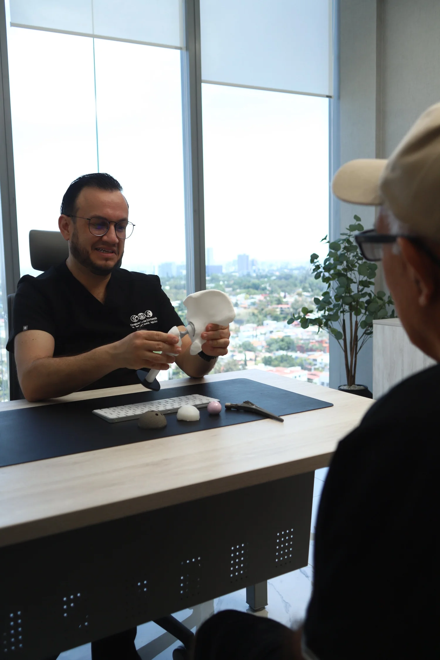 El Dr. Israel Romo, cirujano articular, explica la cadera con un modelo anatómico en su consultorio en Guadalajara
