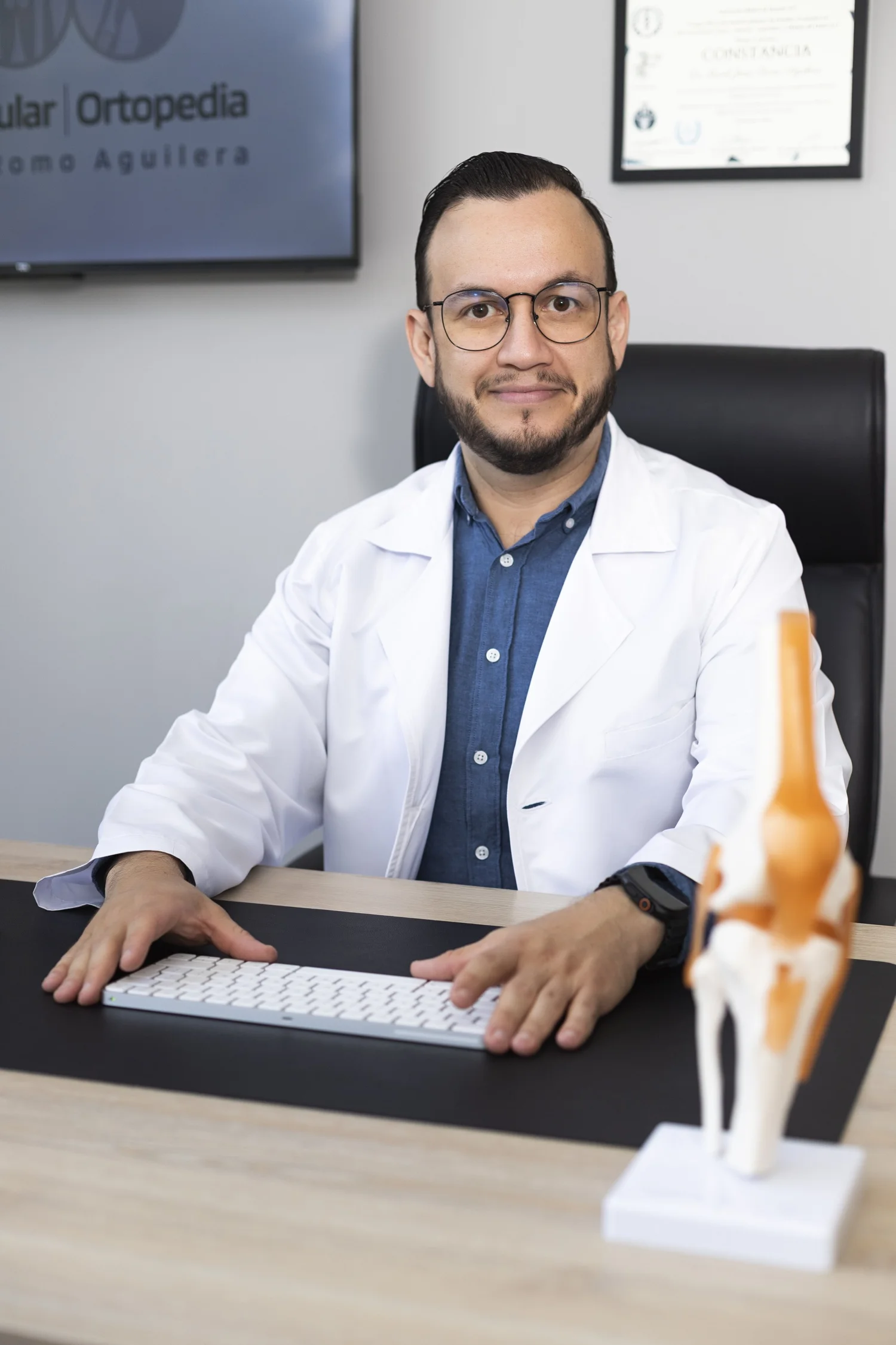 Dr. Israel Romo, especialista en rodilla en Guadalajara, con un modelo anatómico de rodilla