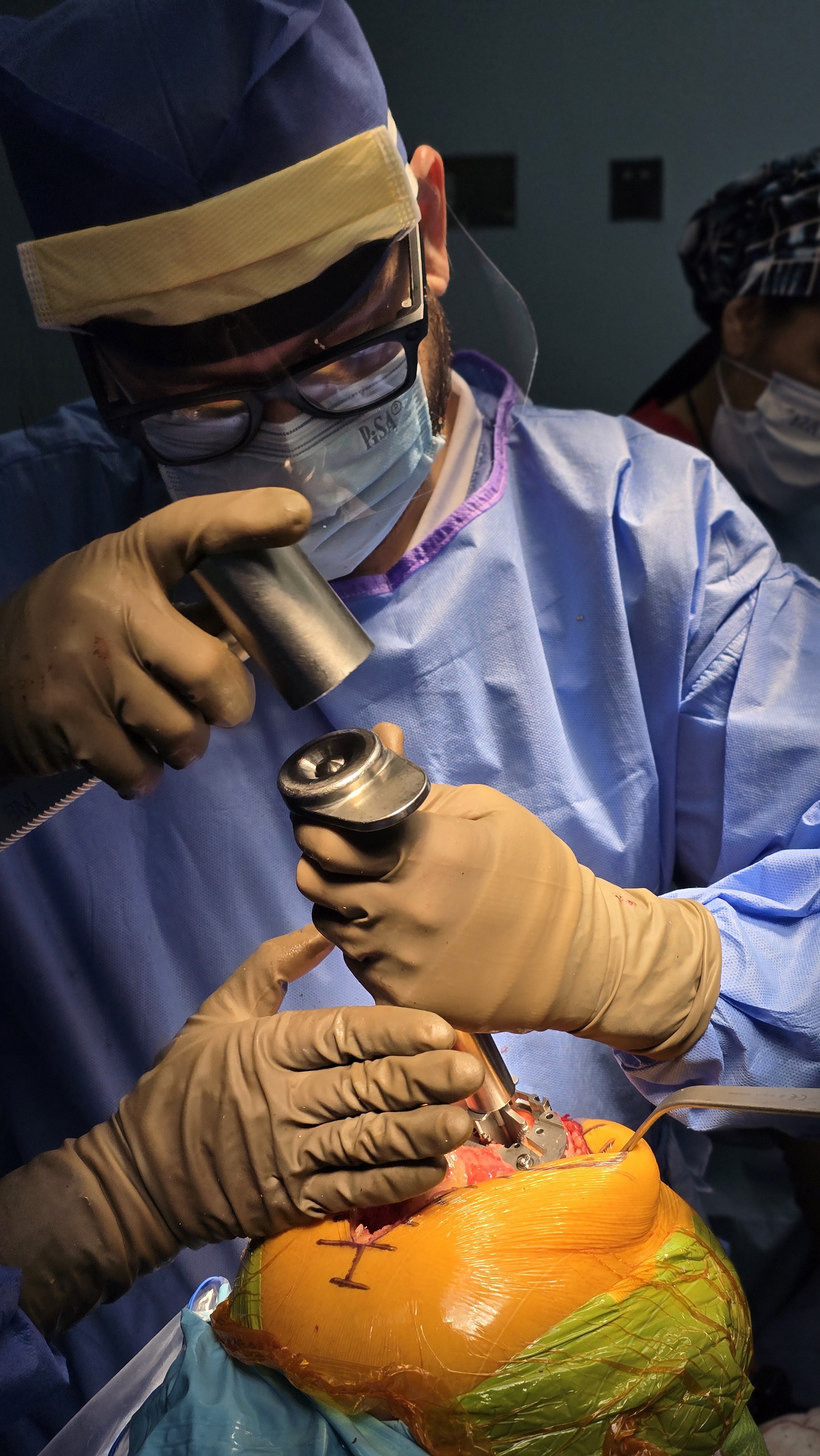 Doctores realizando un procedimiento quirúrgico en un cuerpo donado o en un modelo plástico de un cuerpo, usando instrumentos especializados y guantes de látex.