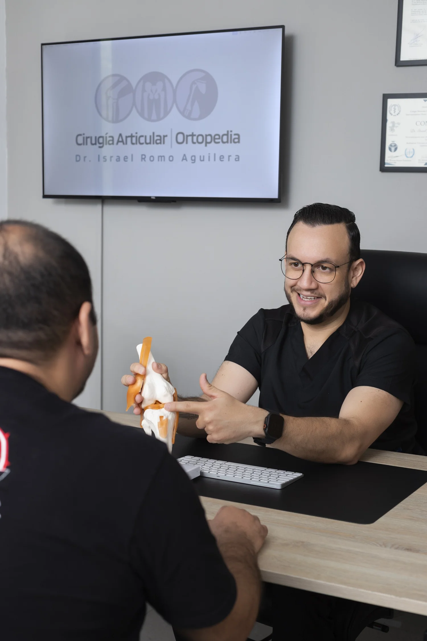 Dr. Israel Romo, especialista en rodilla en Guadalajara, explica la rodilla con un modelo anatómico en consulta